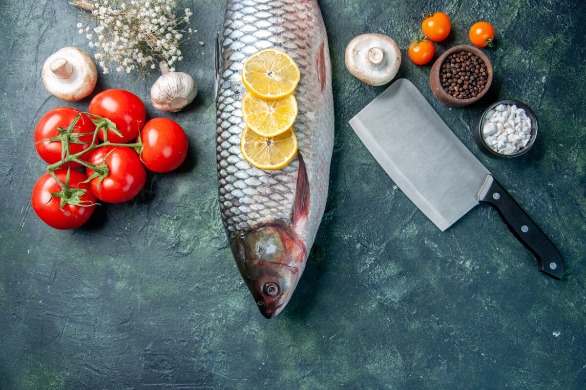 晚餐顶视图新鲜的生鱼肉与柠檬和西红柿在深蓝色的背景肉食物柠檬