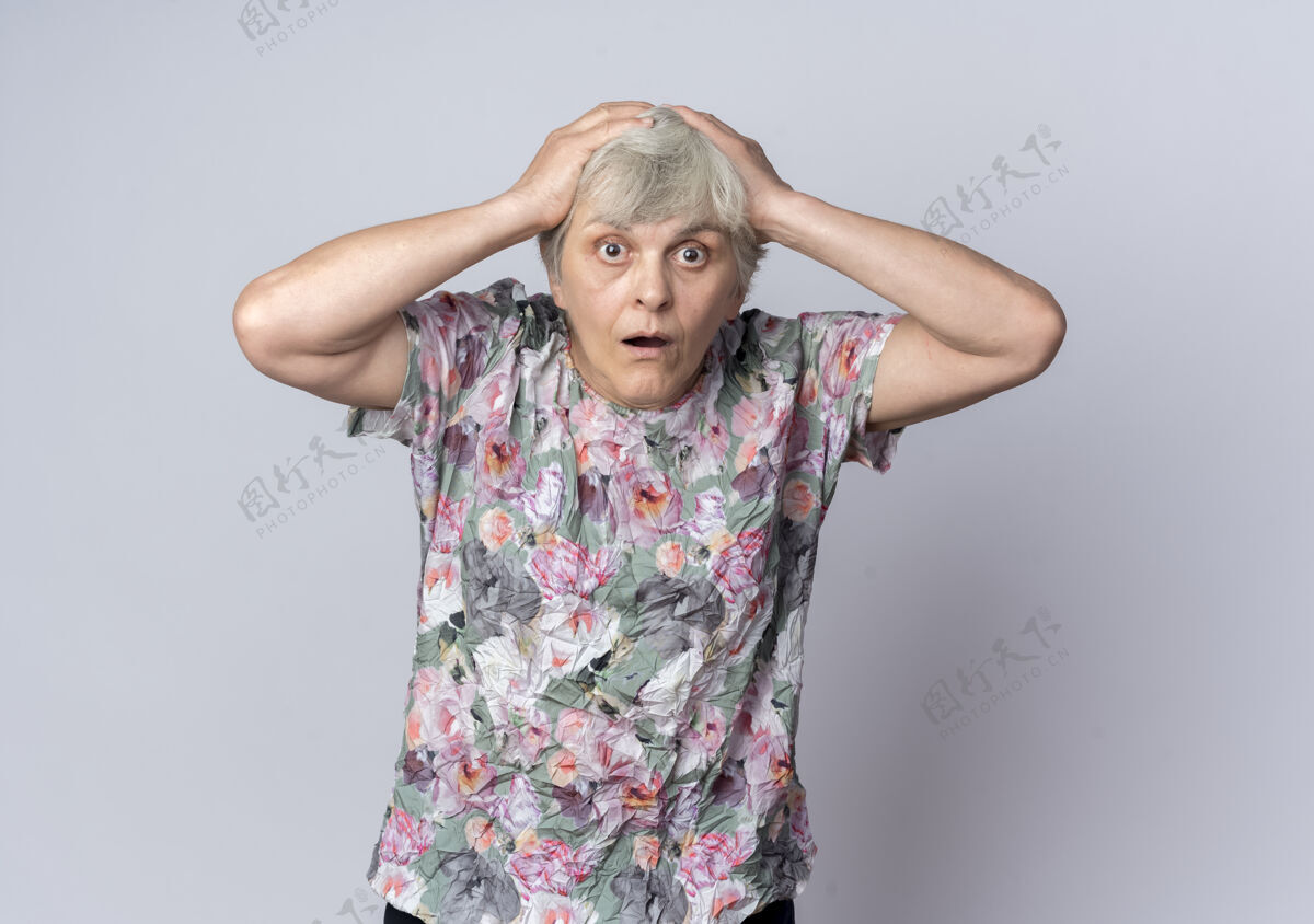 老人震惊的老妇人把手放在头上 看着白色的墙上孤立无援老人手女人
