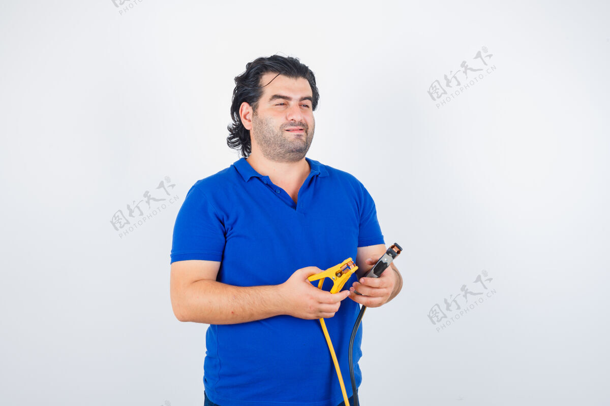 站立一个穿着蓝色t恤拿着建筑工具的成熟男人 看上去很体贴正视图老年人前面成熟