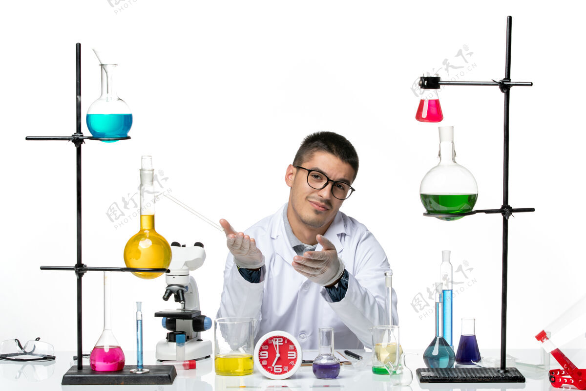 实验室正面图：穿着白色医疗服的男性化学家坐在白色办公桌上 拿着不同的解决方案病毒疾病科学实验室科学疾病视图