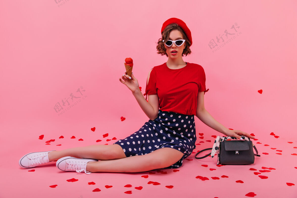 快乐好奇的穿着裙子拿着冰激凌的年轻女子自信的法国女孩戴着贝雷帽在吃甜点贝雷帽成人时尚