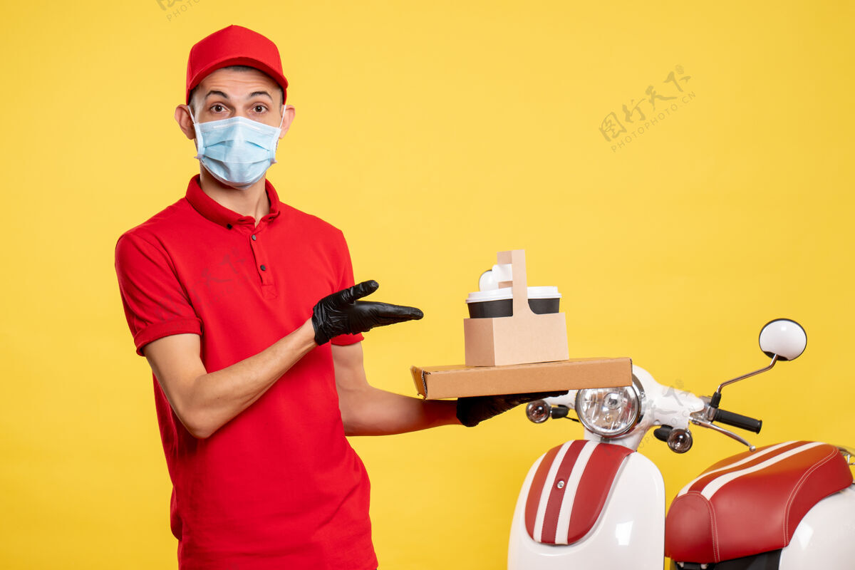 表演正面图：戴口罩的男信使 带着咖啡和黄色盒子 服务于病毒工作服 大流行工作服盒子工作人