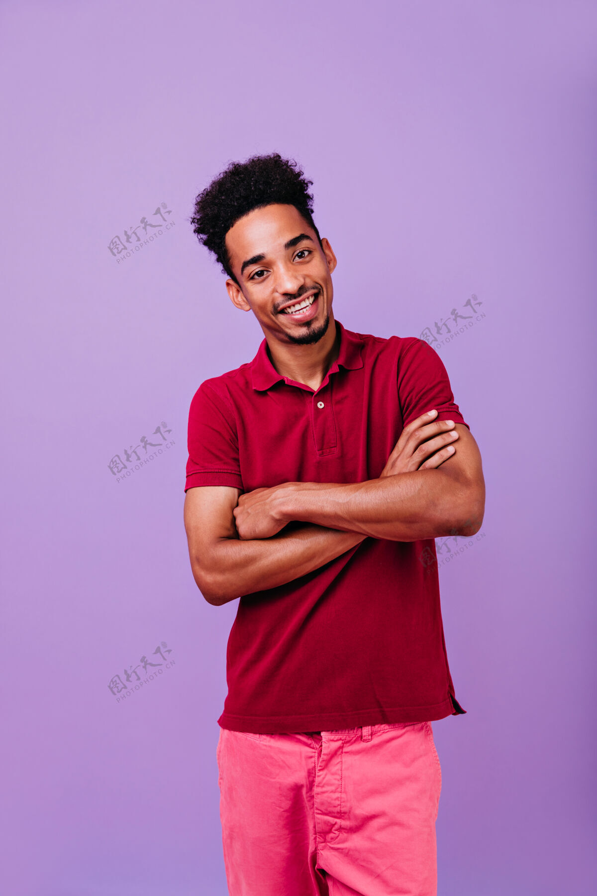 快乐兴奋的时髦男孩交叉双臂摆姿势热情的男模特站在室内的照片非洲快乐时尚
