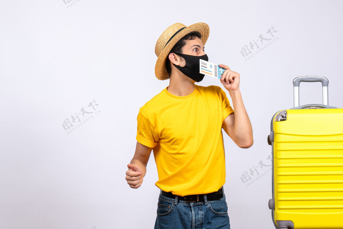 旅行正面图有兴趣的男性游客穿着黄色t恤站在黄色手提箱旁举着旅行票快乐手提箱成人