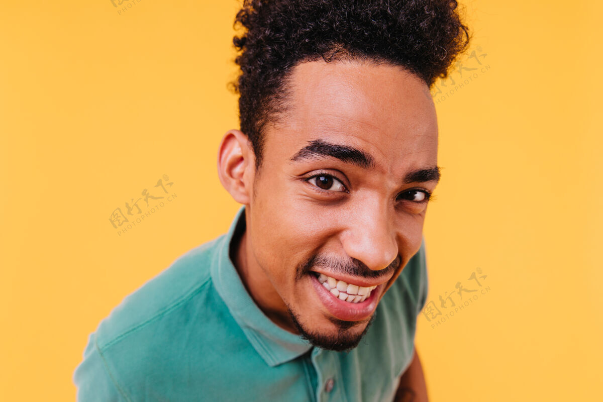 人棕色眼睛的时髦开朗男孩的特写肖像身着绿色服装的非洲男模表达真诚的情感非裔美国人胡须黄色