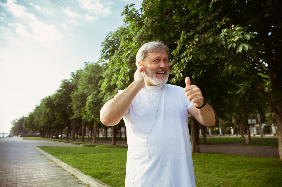 臂章高级男子作为跑步者 在城市街道上使用健身跟踪器高加索男模在夏季早晨慢跑和有氧训练时使用小玩意健康的生活方式 运动 活动理念健康活跃退休