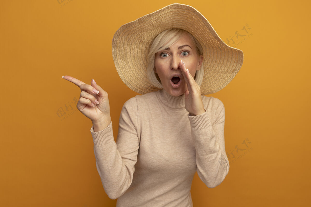 壁板一个戴着沙滩帽的漂亮金发斯拉夫女人惊讶地把手放在嘴边 指着橘子色的一边尖帽子漂亮