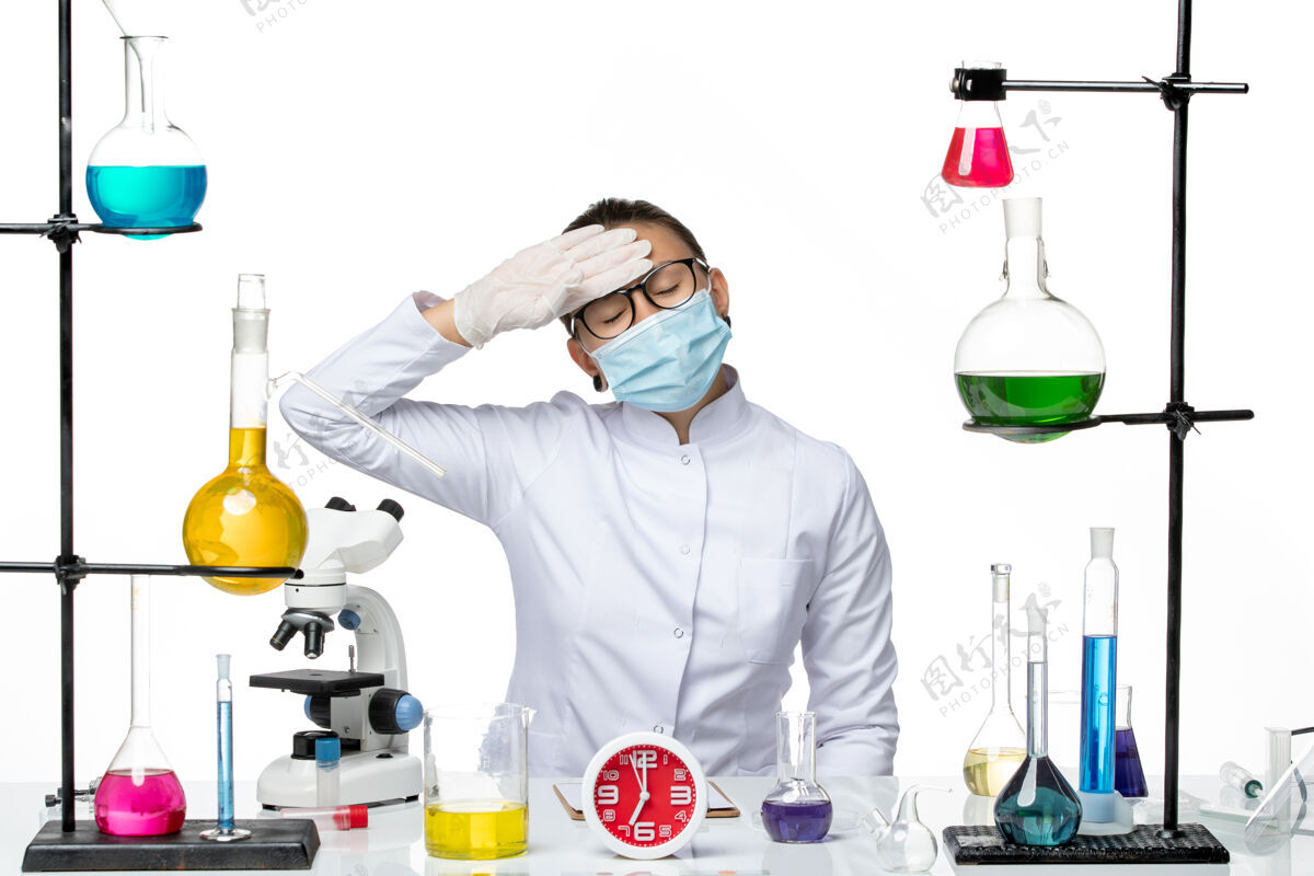 坐前视图穿着医疗服的女化学家带着面罩坐在浅白的背景上化学病毒实验室病毒-飞溅医学专业西装