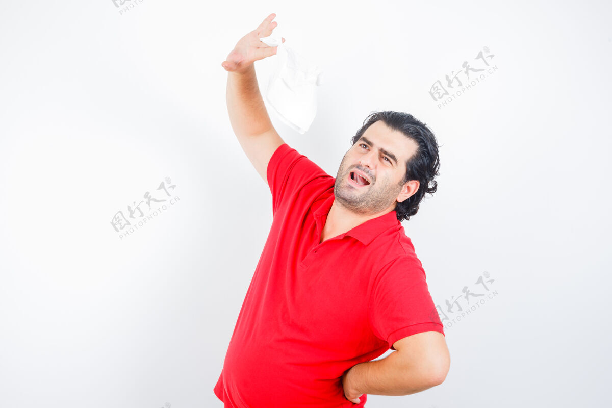 肖像中年男子举起餐巾 手放在臀部 穿着红色t恤 看上去很体贴正面图成人商人男人