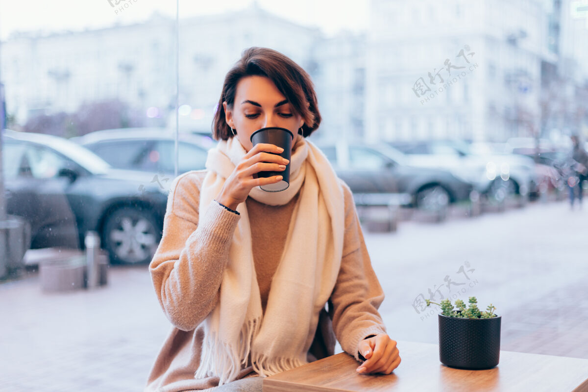 冬天一个女孩在舒适的咖啡馆里用一杯热咖啡取暖热年轻羊毛