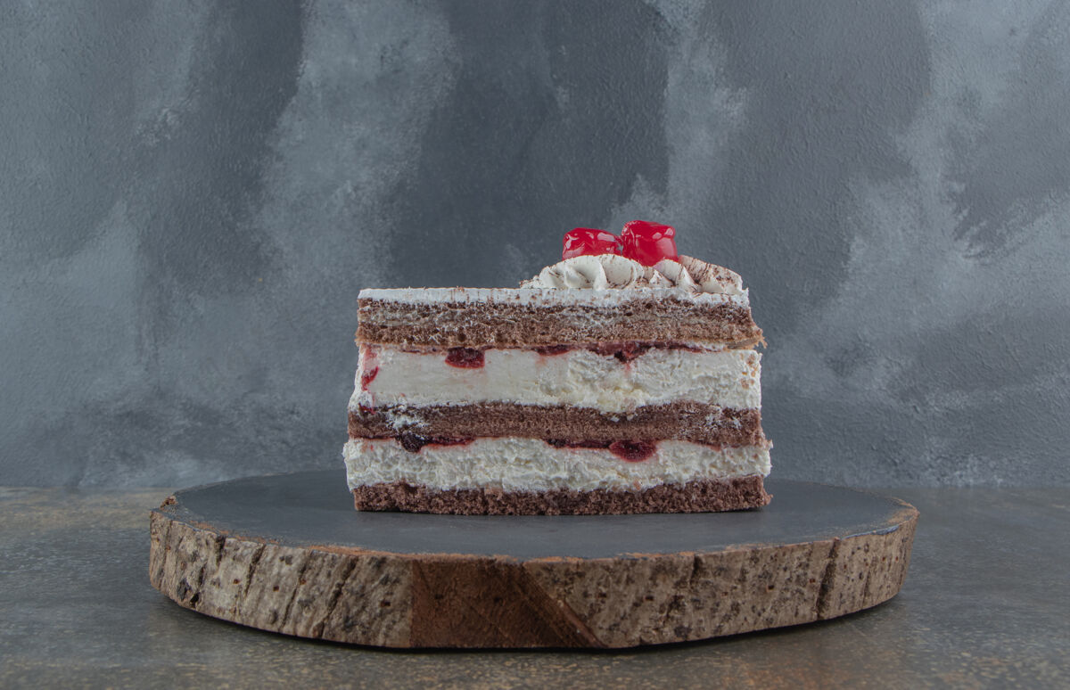 美味奶油樱桃蛋糕片放在一块板上糕点可口切片