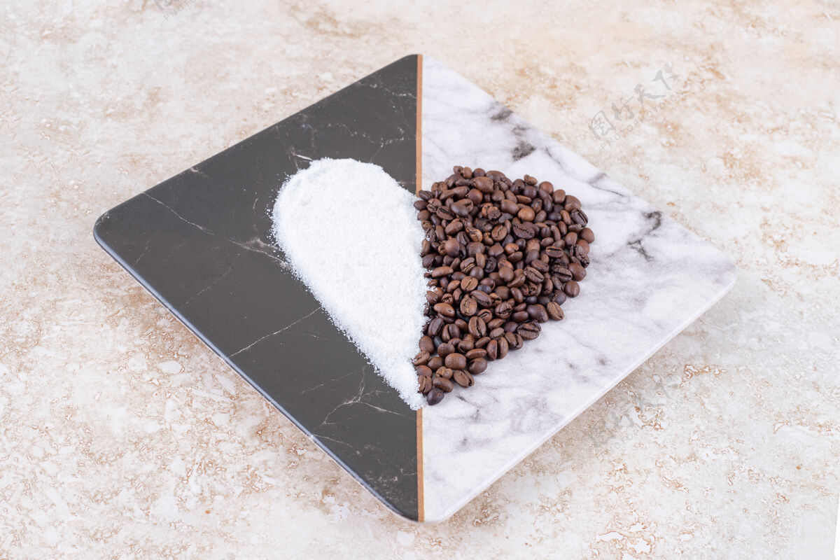 美味糖和咖啡豆在大理石板上排列成心形糖芳香豆