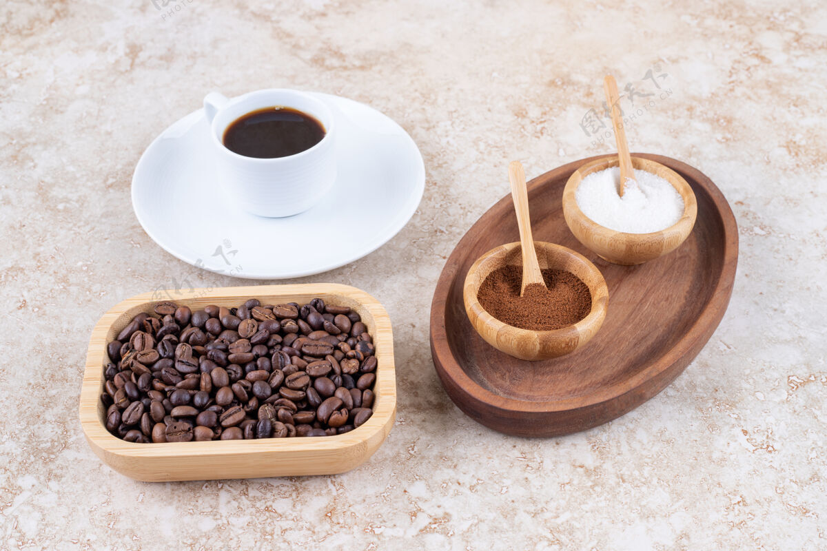 咖啡在一杯咖啡和一碗咖啡豆旁边放着几碗糖和磨碎的咖啡粉的小托盘茶碟豆子美味