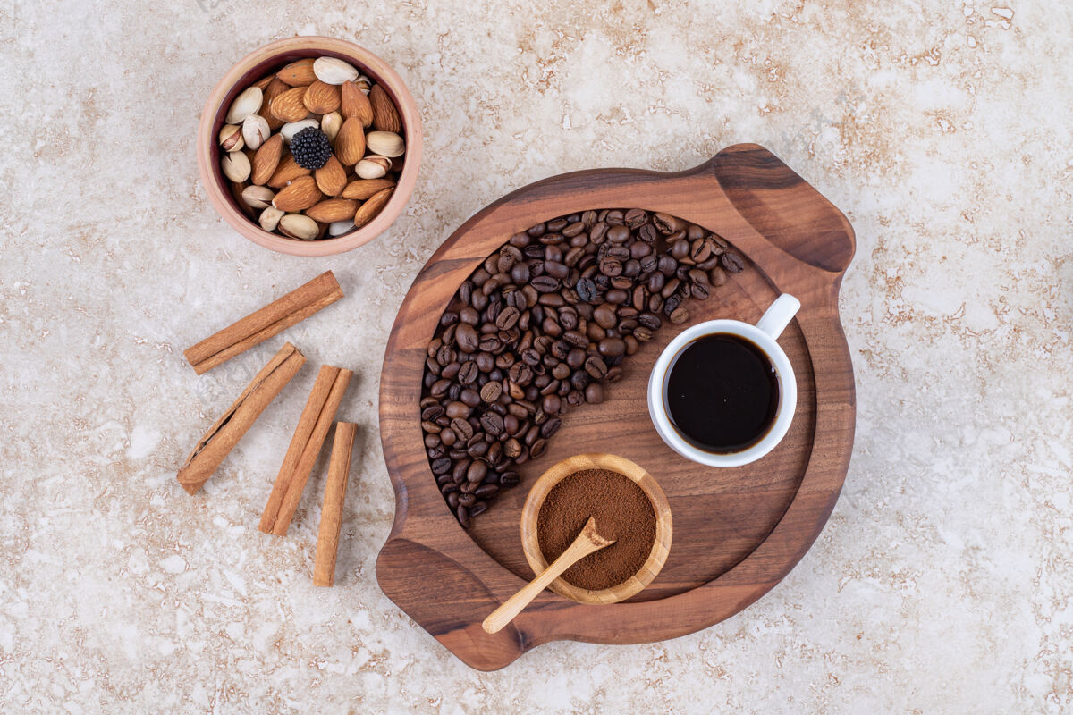 咖啡咖啡托盘旁边的肉桂棒和一小碗各式各样的坚果芳香咖啡粉咖啡粉