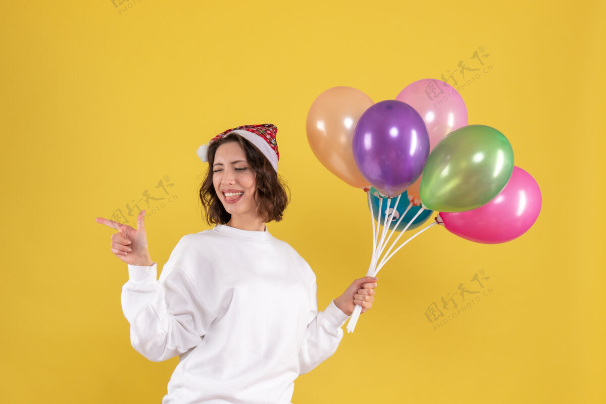 聚会正面图美丽的女性手持彩色气球站在黄色的举行漂亮的女人欢呼