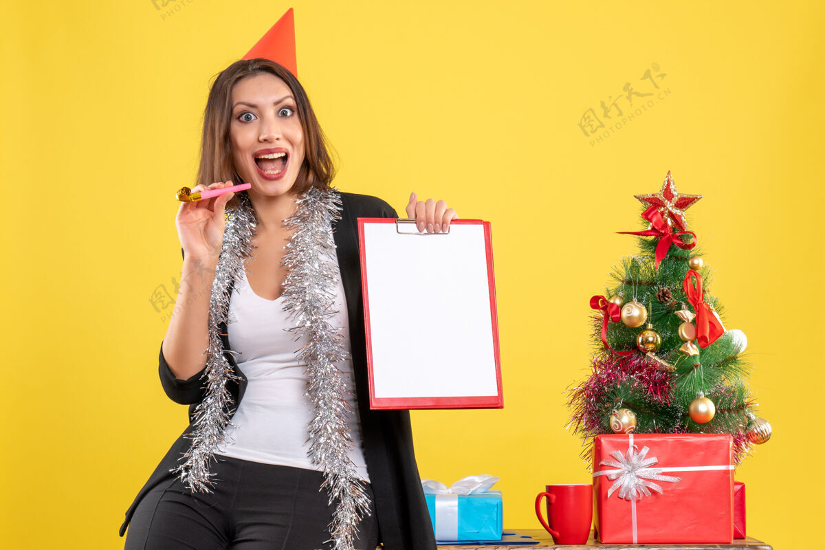 黄色圣诞心情带着微笑的美女拿着文件在黄色的办公室里圣诞节肖像美丽的女士