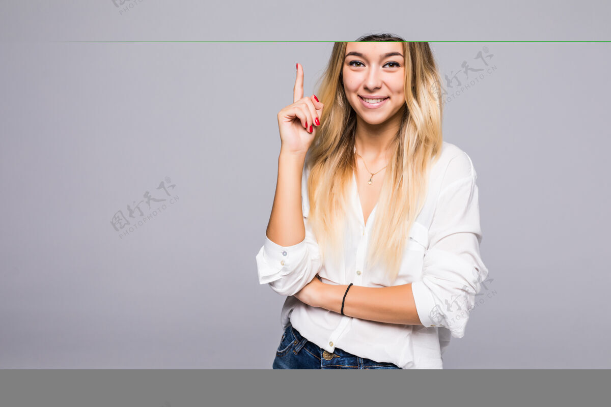 聪明好主意成功的微笑的女人站在灰色的墙上 用手指向上选择女性脸