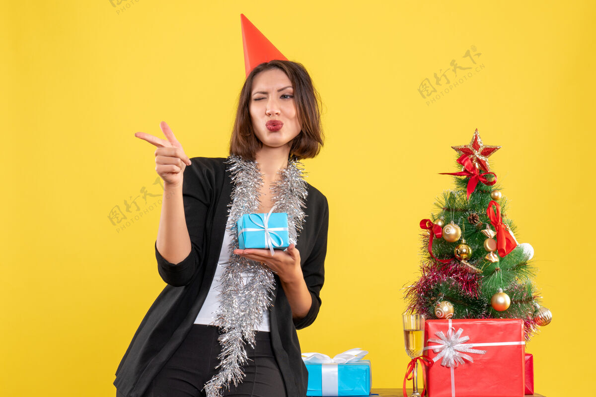 性感圣诞气氛与美丽的女士拿着礼物指着黄色办公室的东西美丽的女士成人指向