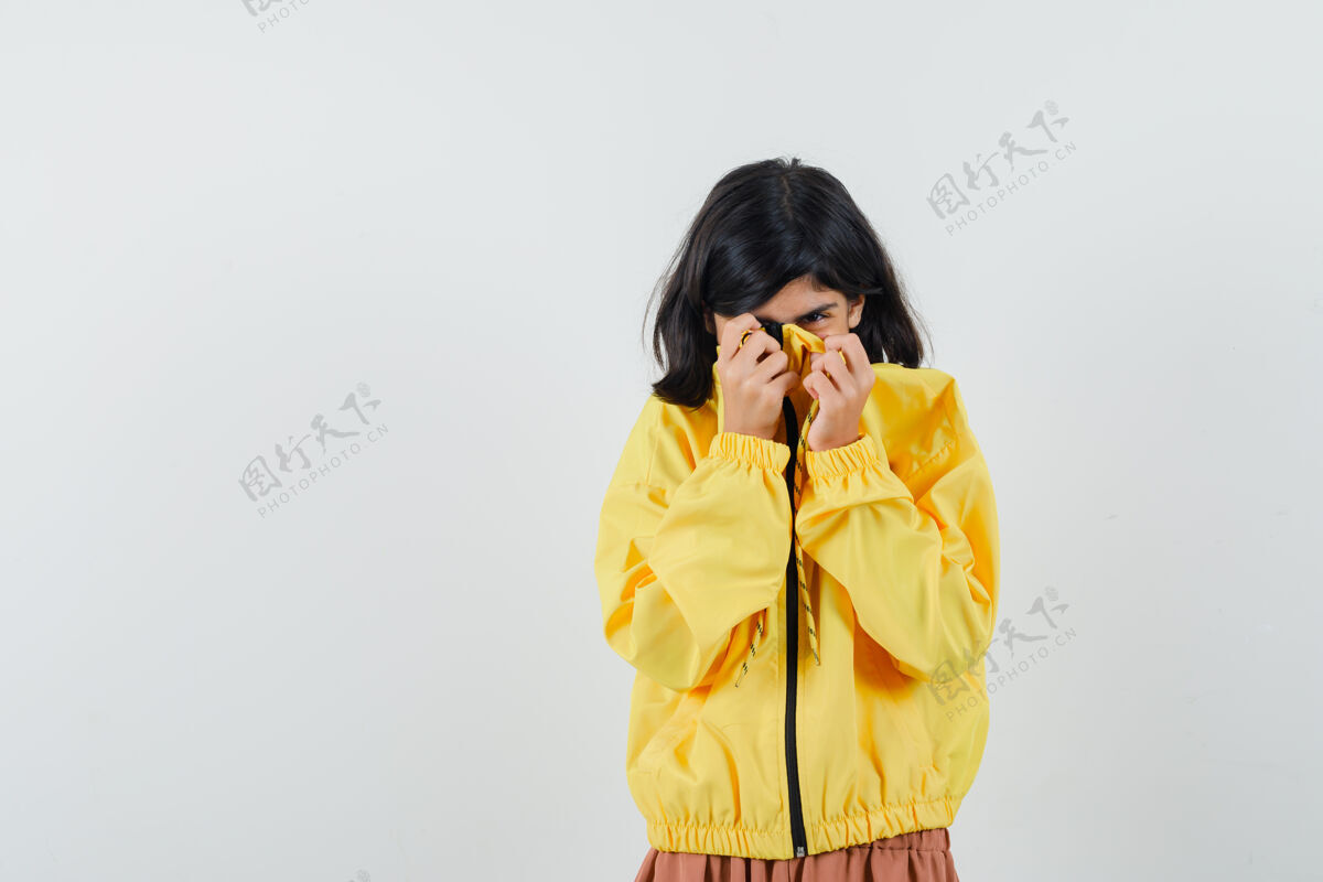 女性穿着黄色连帽衫的小女孩拉着她的衣领在脸上 看起来很害怕 正面视图西班牙人害怕脸