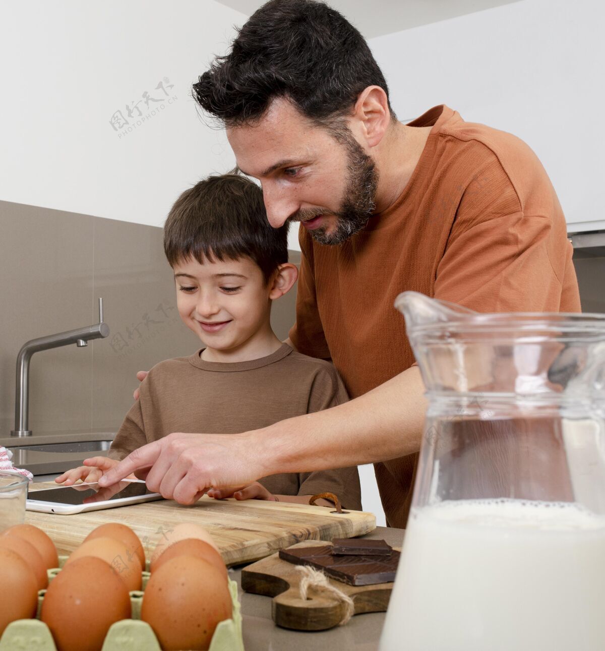 烹饪中枪男子和小孩在厨房里用平板电脑室内烹饪膳食