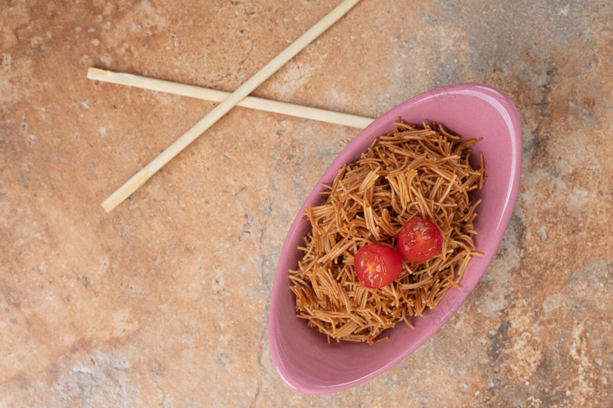 美味用筷子在粉红色的碗里炸西红柿粉丝高质量的照片切片面食筷子