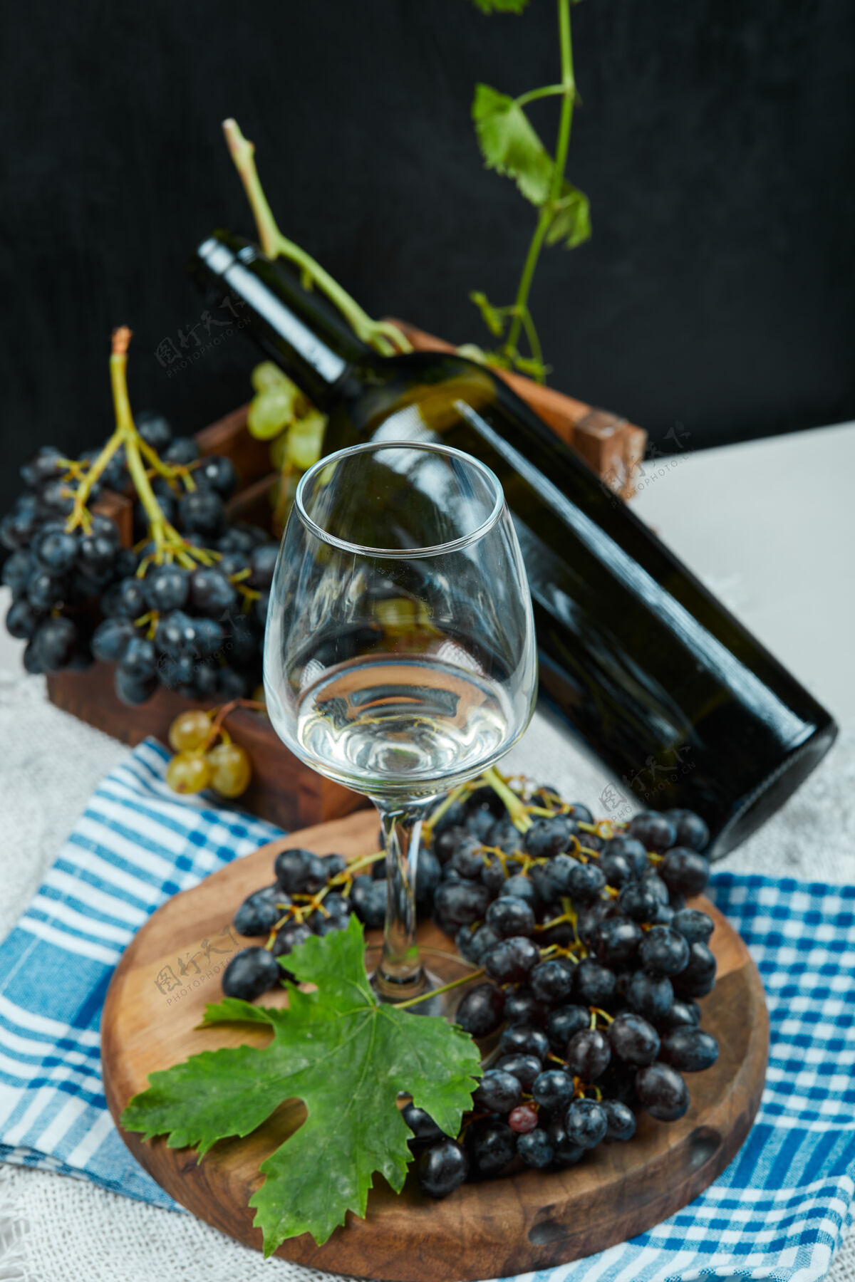 季节一簇葡萄配一杯葡萄酒和一瓶蓝色桌布放在白色的桌子上高质量的照片大自然餐桌水果