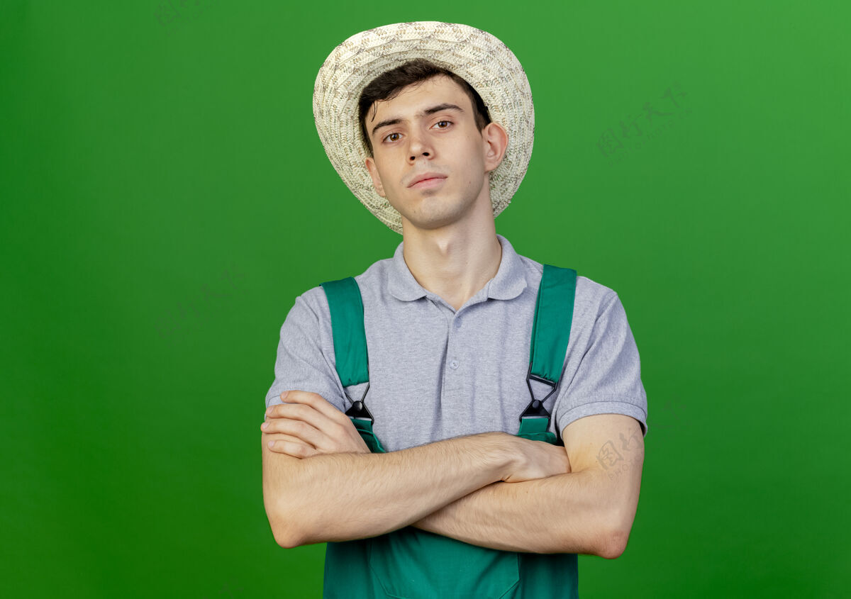 绿色自信的年轻男园丁戴着园艺帽 交叉双臂站在绿色的背景上 有复制空间帽子园艺花园