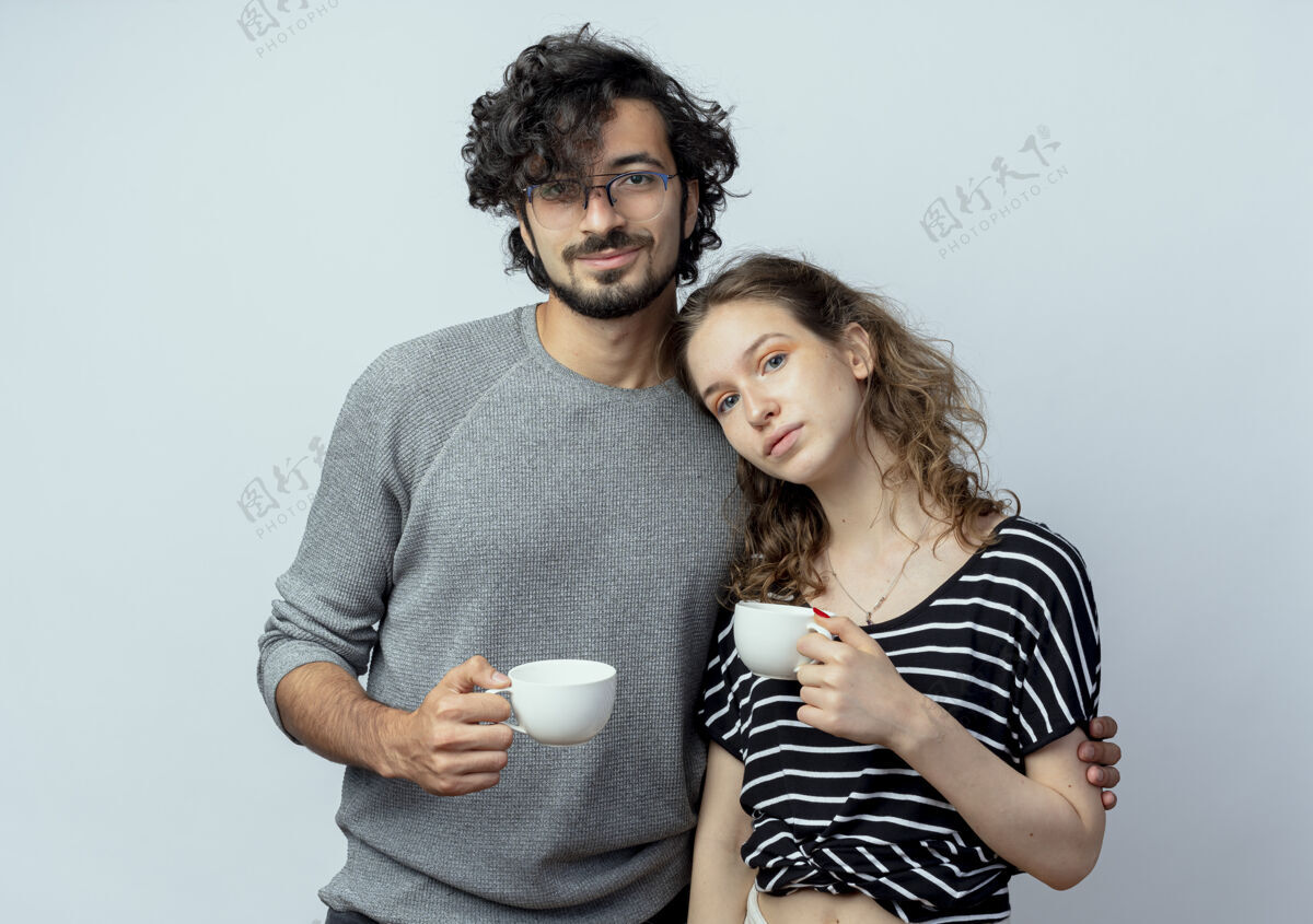 情绪年轻漂亮的情侣男女在爱情中幸福地捧着咖啡杯在白色的背景下感受积极的情感积极抱着感觉