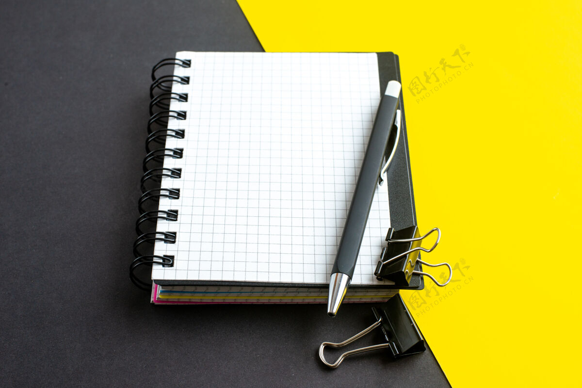 螺旋笔记本侧视图螺旋笔记本上的书和笔在黑黄色背景与自由空间活页夹钢笔办公室