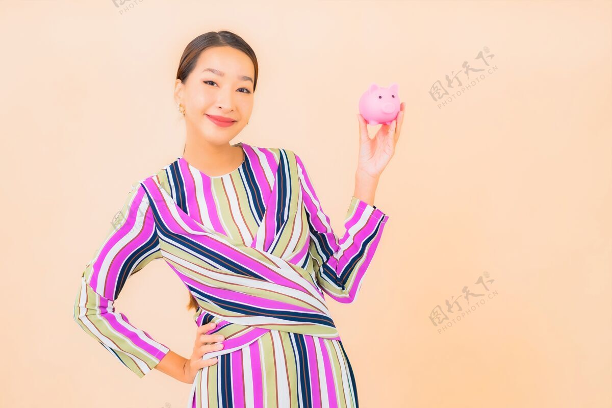 小猪银行肖像美丽的亚洲年轻女子与粉红色的小猪银行的颜色成人昂贵肖像