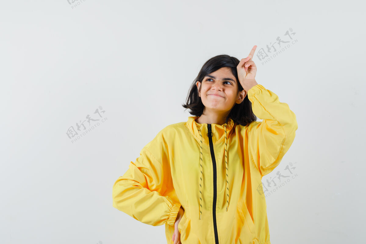 头穿着黄色连帽衫的小女孩把手指举过头顶 看起来很梦幻 正面视图肖像手指房间