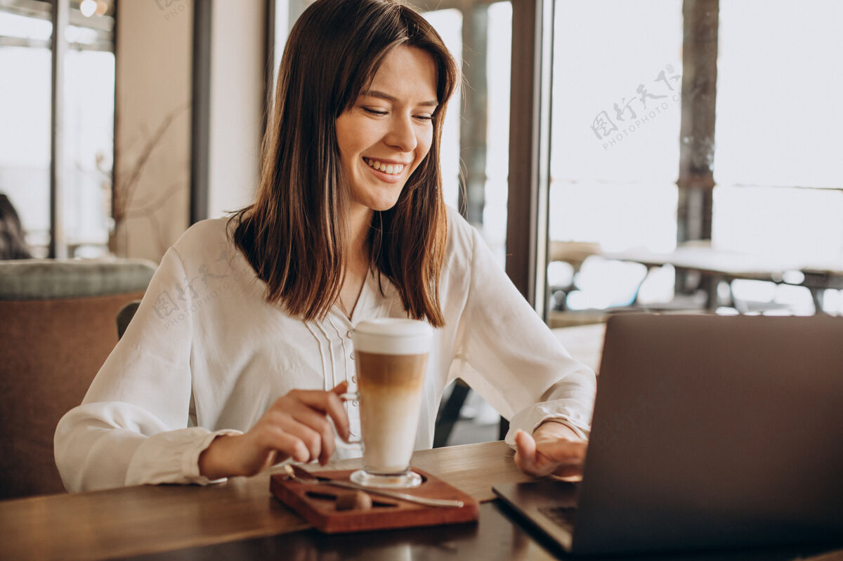 Pc年轻的女商人在咖啡馆上网 喝咖啡拿铁在线学习现代