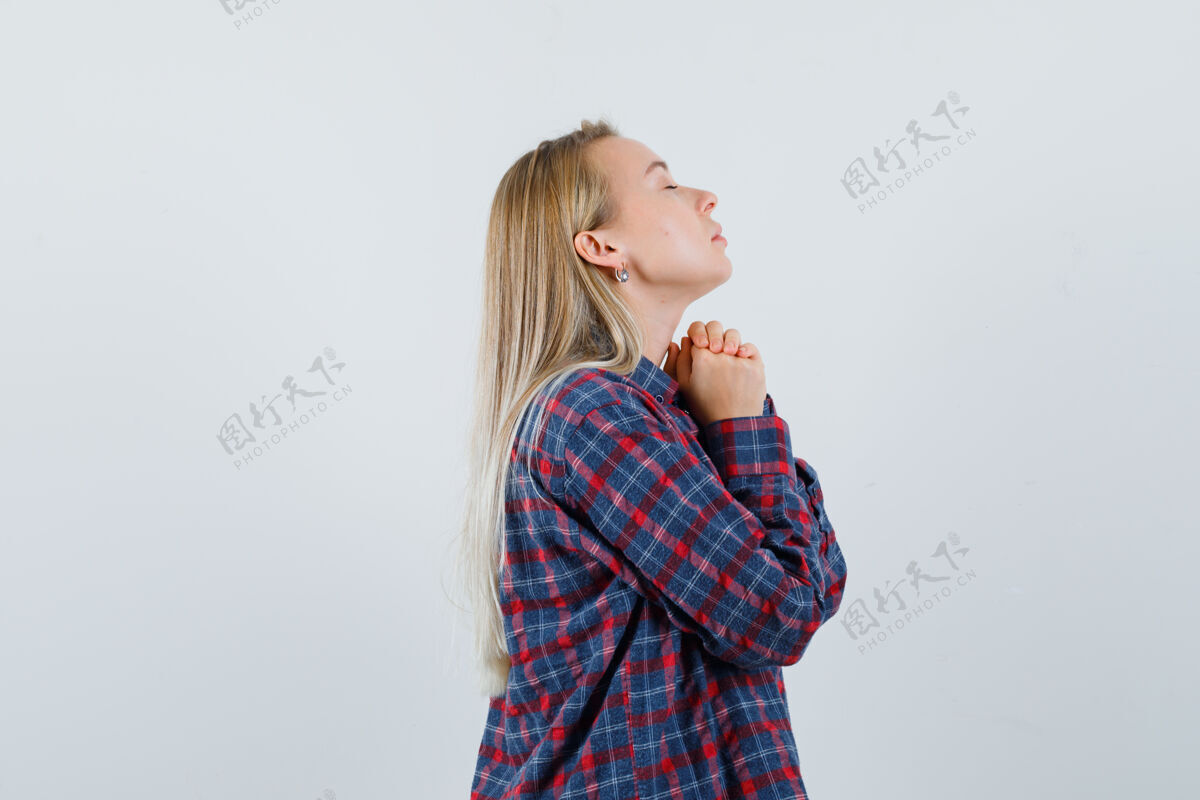 祈祷金发女人站在祈祷姿势在格子衬衫和寻找重点前视图站立姿势头发