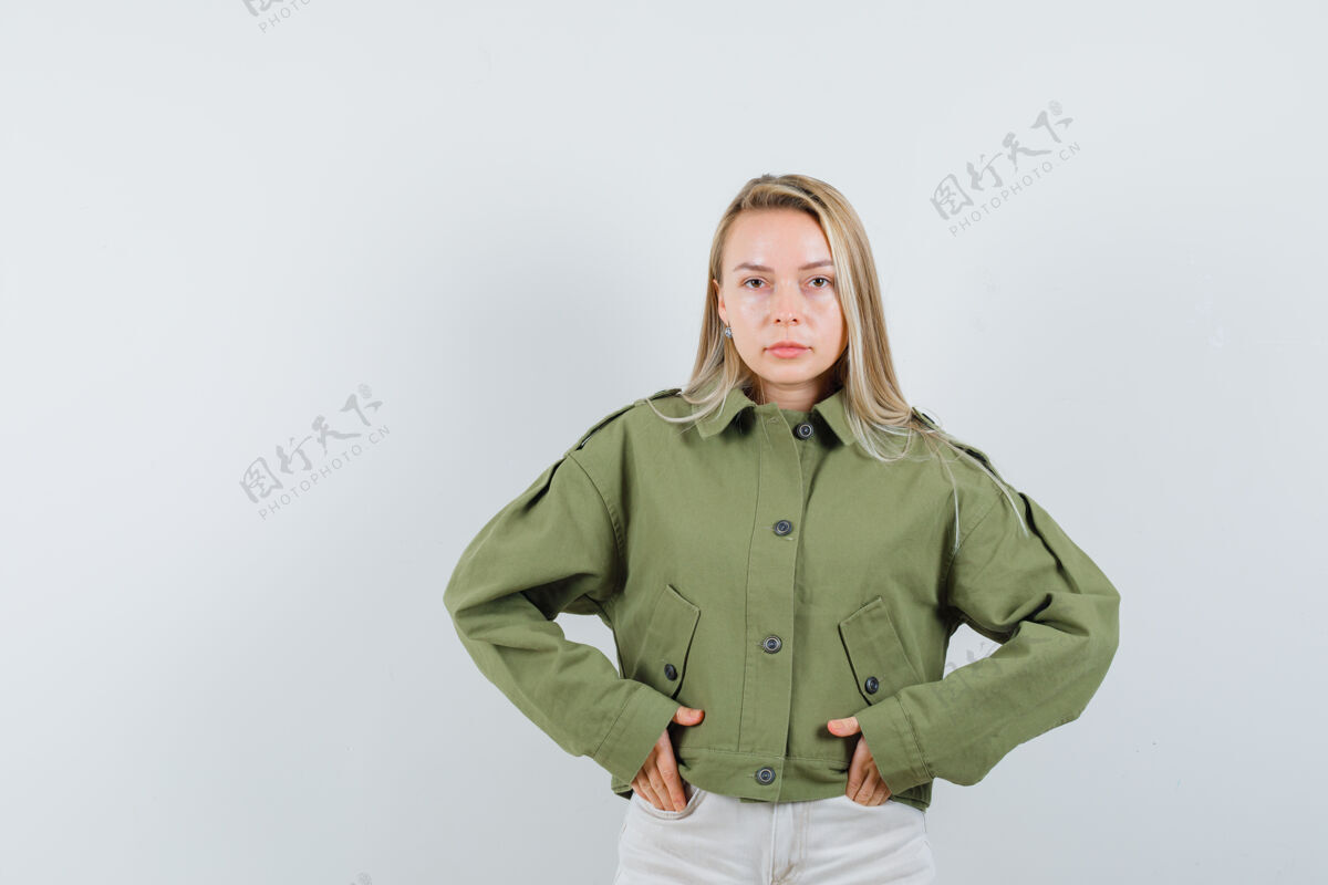 自然穿着绿色夹克的年轻女性 牛仔裤手插在口袋里 表情严肃 正面照脸夹克女性