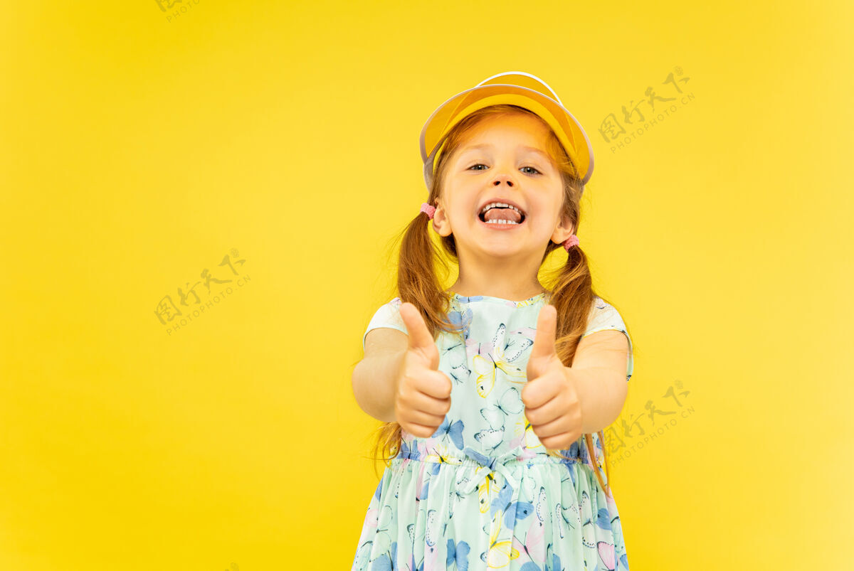 长美丽动情的小女孩被隔离在黄色背景上半幅快乐的孩子的肖像 穿着裙子 戴着橘黄色的帽子 表现出一种ok的姿态夏天的概念 人类的情感 童年欢呼脸年轻