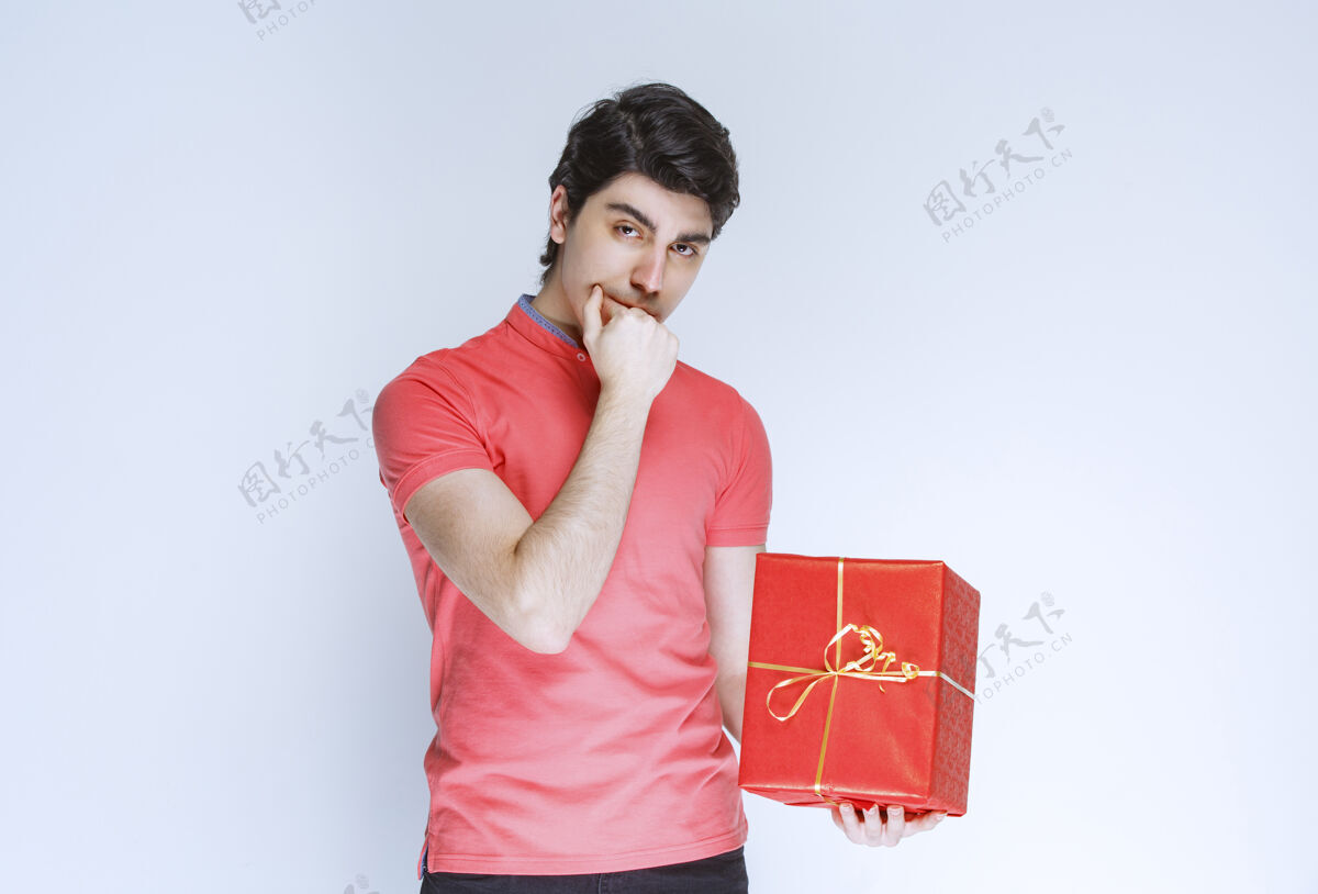 成人拿着红色礼盒的男人把手放在嘴边思考着姿势人男性