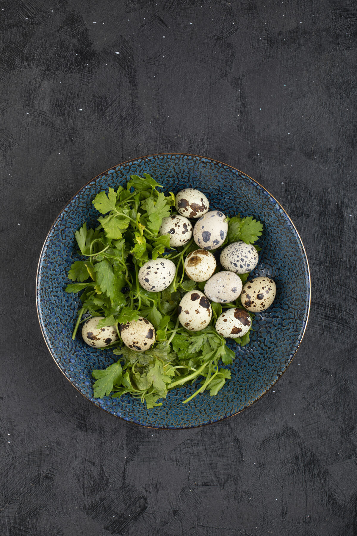 蛋壳新鲜生鹌鹑蛋和欧芹叶放在黑色的盘子里新鲜食品有机
