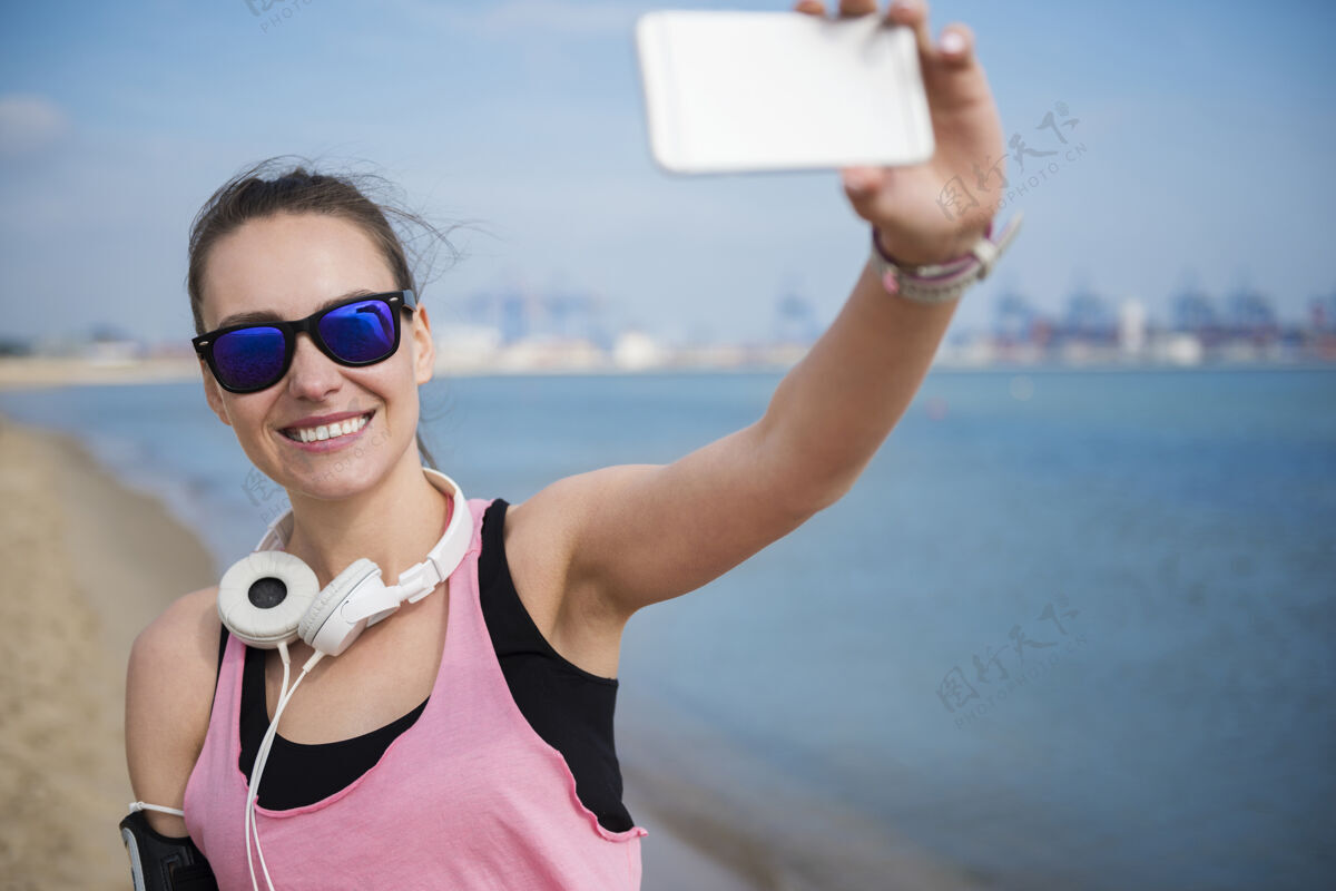 海滩特写在海边慢跑的健康年轻人摄影自拍手机