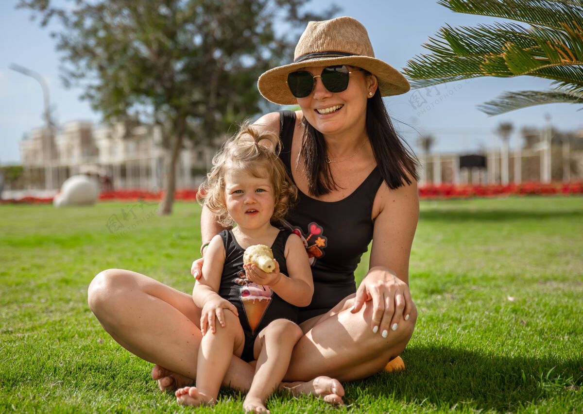 棕榈树小女孩和妈妈在夏天的草丛中掌心热家庭夏天