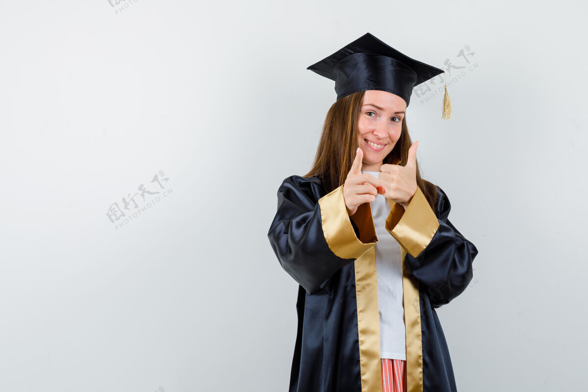 年轻年轻的女毕业生穿着学院服站在一边 看起来很高兴正面图指向漂亮亚洲人