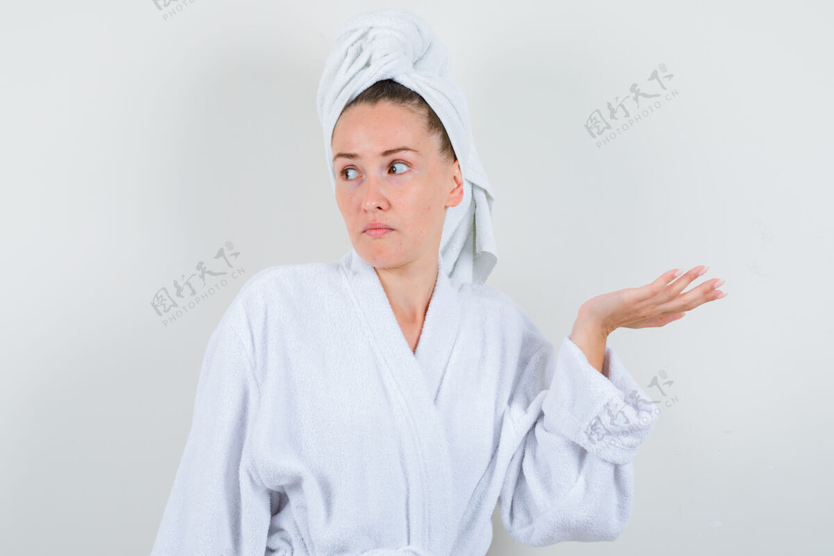 微笑在白色浴袍 毛巾和看起来困惑的前视图显示无助的姿态的年轻女孩的肖像人物困惑青少年