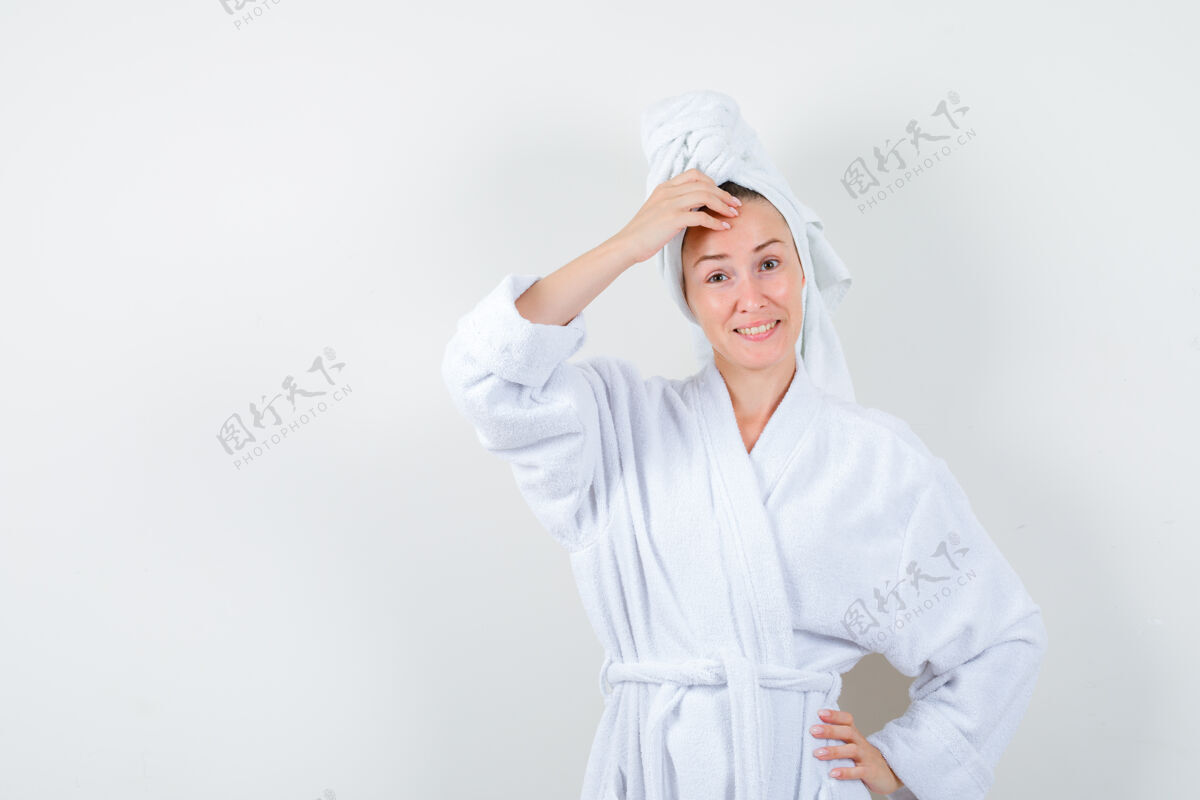 漂亮年轻的女人手放在头上 穿着白色浴衣 毛巾 看上去很快乐正视图人时尚时尚
