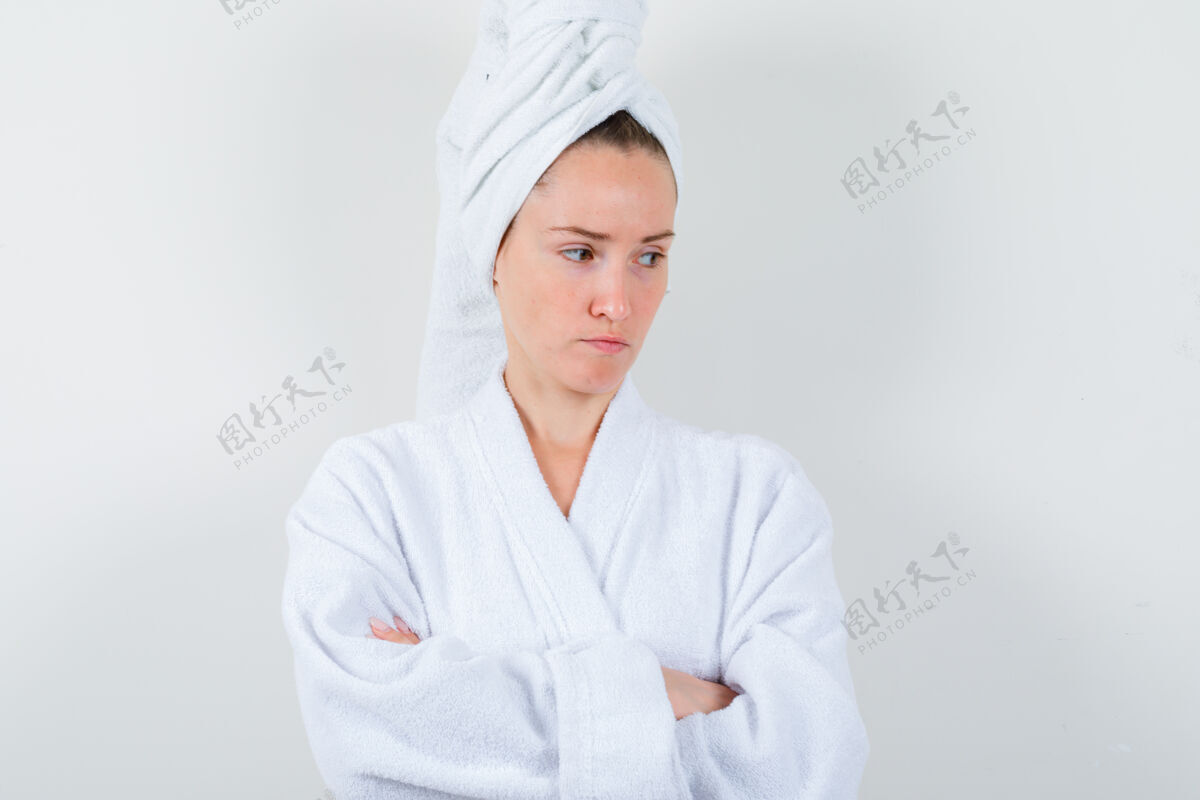 心烦年轻女子交叉双臂站在白色浴衣 毛巾和看起来沮丧 前视图皮肤前面卷发