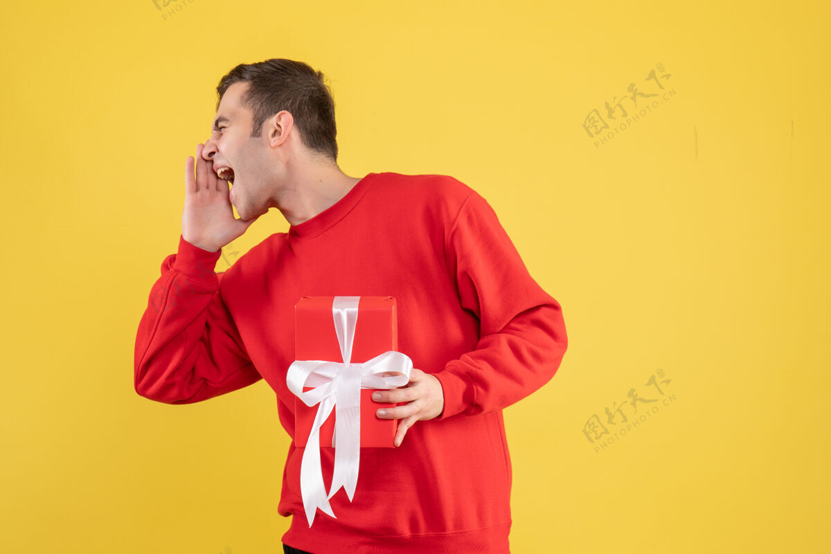 视图正面图穿红色毛衣的年轻人在黄色背景上大声喊叫年轻人微笑人物