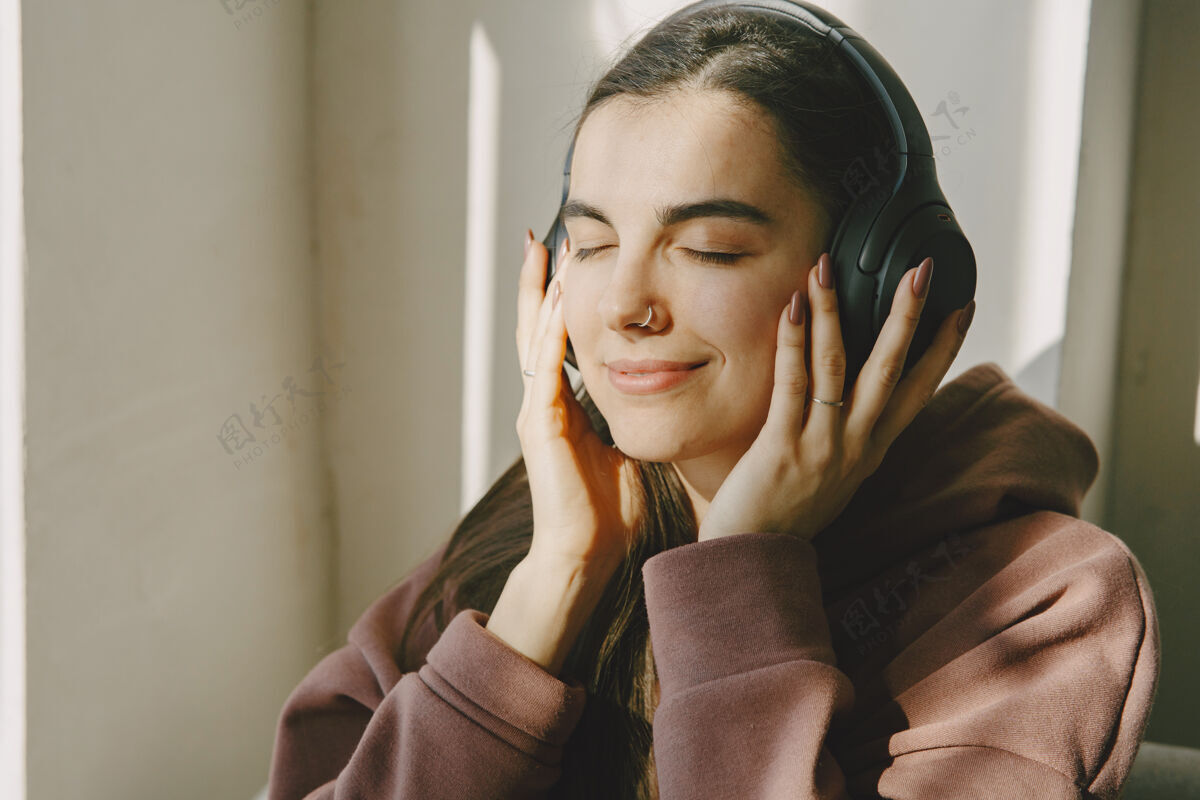 房子戴着耳机的快乐女孩在家听音乐学生音乐成人