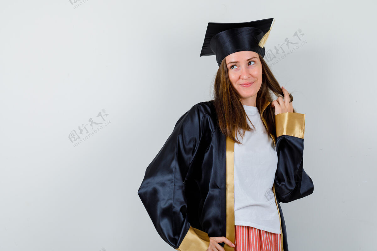 教育女毕业生穿着制服 穿着休闲服 抱着自己的头发摆姿势 看起来很梦幻 正前方的景色长袍休闲Campus