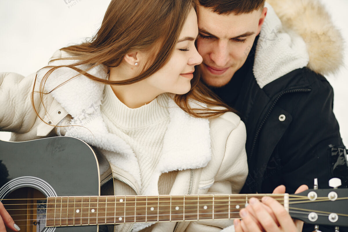 外面一对夫妇坐在雪林中的生活方式照片人们在户外度过寒假一对夫妇带着吉他女性关系肖像