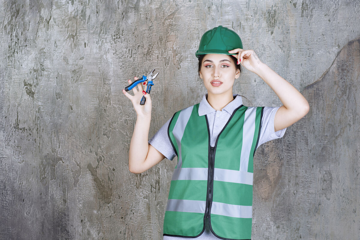 工具女工程师戴着绿色头盔拿着钳子进行修理工作职员混凝土女人