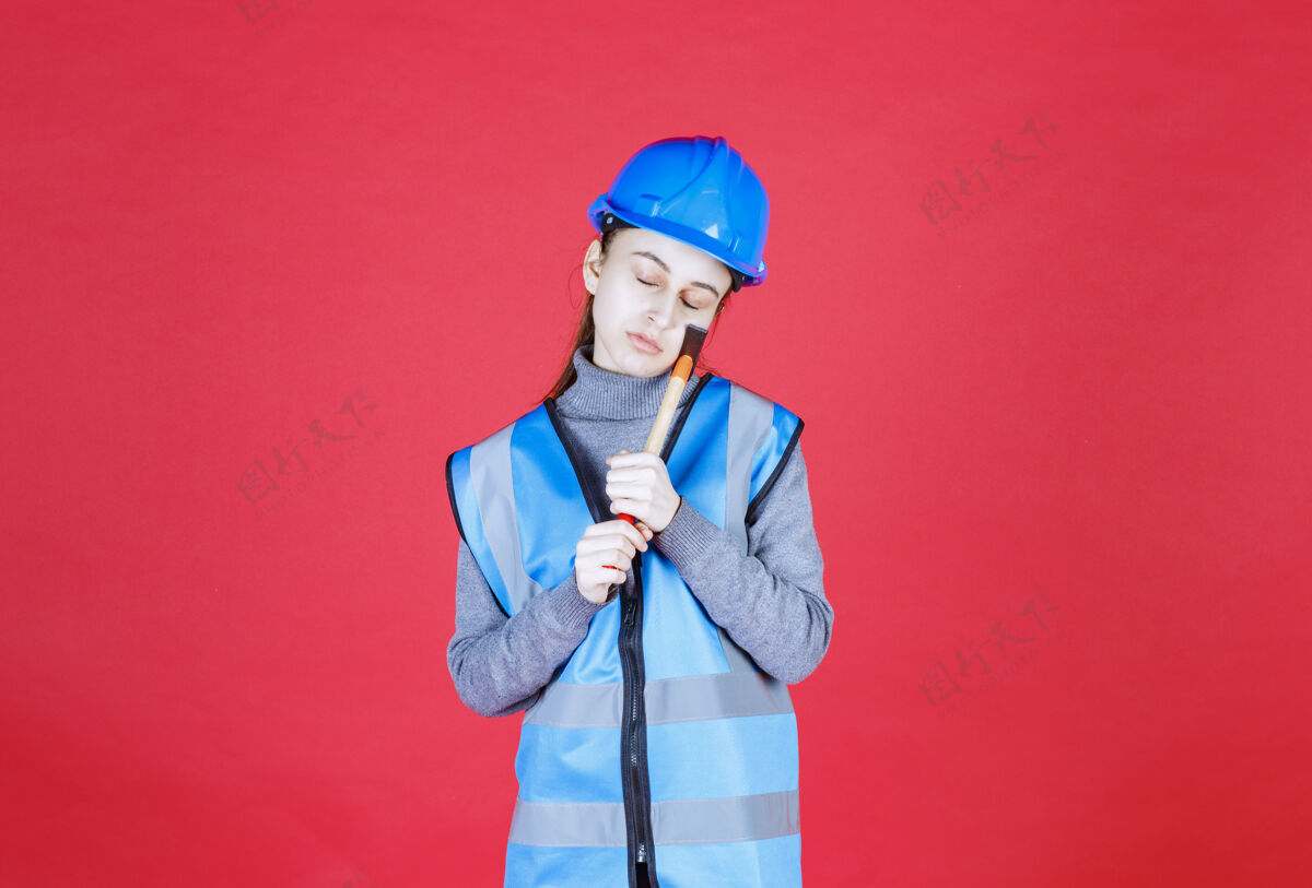 疲倦戴蓝盔的女工程师拿着木斧头睡觉工人成人聪明