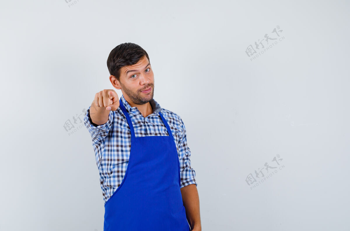 成人穿着蓝色围裙和衬衫的年轻男厨师烹饪男士年轻